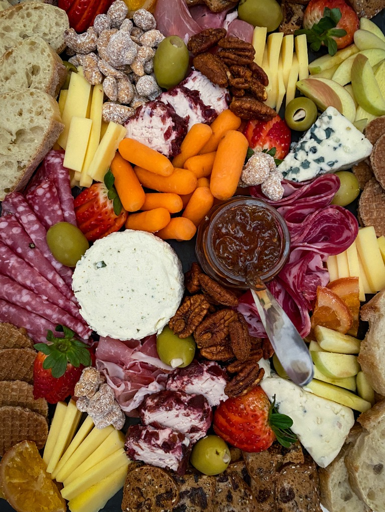 an elegant cheese board with blue cheese, goat cheese, gouda, nuts, and fruits